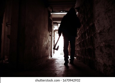 Silhouette Of Man Holding Axe. Hatchet In Arm In Dark Hallway. Scary Homicide Scenes