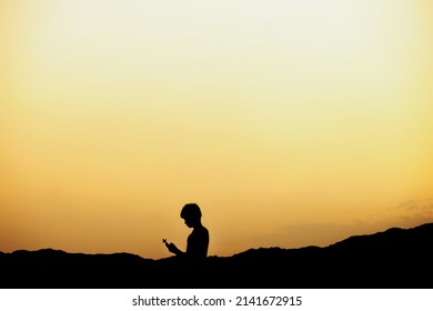 Silhouette of a man holding a cross and praying to god at sunset. concept of religion.