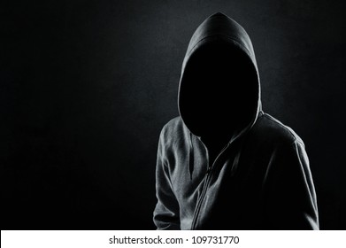 Silhouette of man in the hood or hooligan over dark concrete background with copy space - Shutterstock ID 109731770