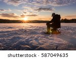 Silhouette of a man ice fishing on a lake in Norway at sunset.