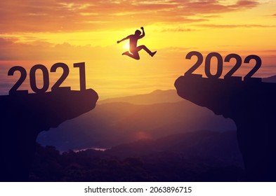 Silhouette Mann springen zwischen 2021 und 2022 Jahren mit Sonnenuntergang Hintergrund, Erfolgreiches neues Jahr Konzept.