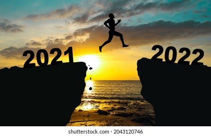 silhouette man jump from the mountain from 2021 to 2022 years with the sunset or sunrise background. Happy and success growth with new year 2022 concept - Shutterstock ID 2043120746