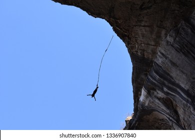 Silhouette of a man jumping in a cave hanging high on a cord. Upwards view. Bungee jump in Pohodna Cave, Bulgaria. 