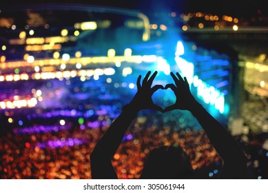 Silhouette of a man making heart from hand gestures, vintage look on photo and crowd background
