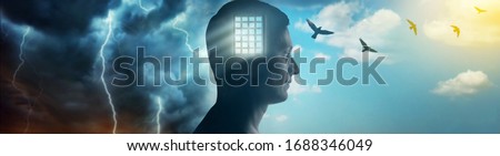 Silhouette of a man on the background of the prison bars, the sky and birds flying away as a symbol of freedom. Concept on the topic of psychology, psychiatry, religion.
