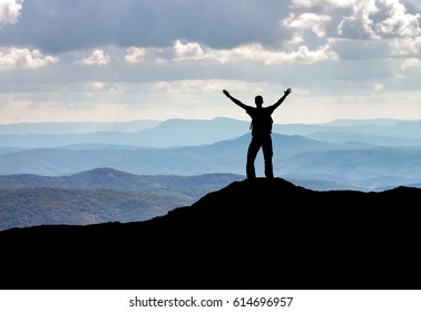 Silhouette of a man on a mountain top. Person on the rock. Sport and active life concept
