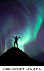 A Silhouette Of A Man On The Peak With Northern Lights. Dream Come True With Aurora Borealis. Northern Light Dancing Over A Man Who Is Watching A Natural Night Show. The Best Moment Of Travelers Life.