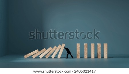 Silhouette of a man in panic against collapsing wooden dominos. Business crisis and failure concept in wide view.