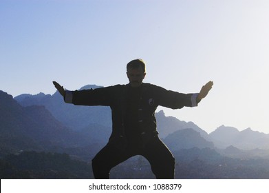 Silhouette Of A Man Practicing Tai Chi In The Desert Morning.