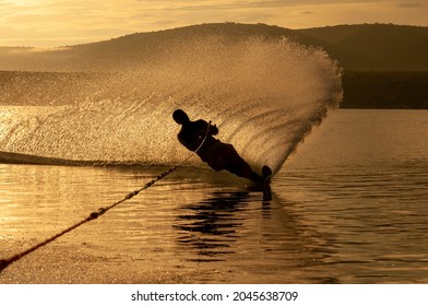 Silhouette Of A Man Practicing Water Ski Slalom At A Lake In The Sunrise Sunset Making Water Spray In Mexico. Selective Focus