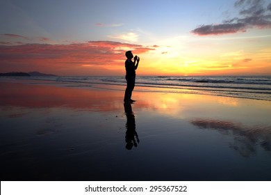 Silhouette Of Man Praying During Sunset.