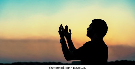 Silhouette Of Man Praying At Sunset