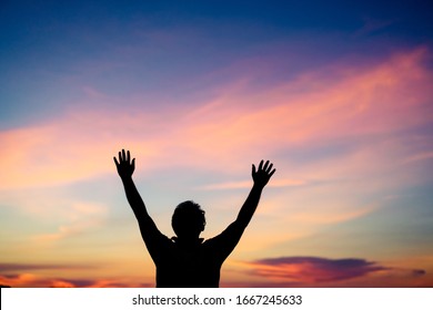 Silhouette man praying and worship to GOD on the sunset sky.Man praying to GOD in the morning.Young man hand praying,Raised Hands in prayer.Concept for faith,Praise the lord spirituality and religion.