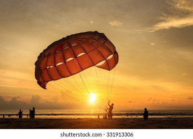 Silhouette Of Man Is Preparing Para Sailing At The Sunset Beach In Thailand