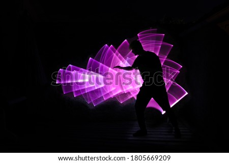 Silhouette of a man in profile with outstretched arm. Abstract light saber shape with lightpainting.