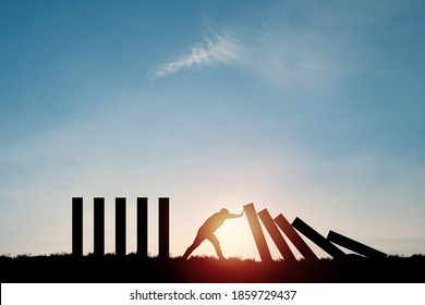 Silhouette man pushing rectangle  block which falling to stop dominos others rectangle standing with blue sky. Risk and crisis management concept. - Shutterstock ID 1859729437