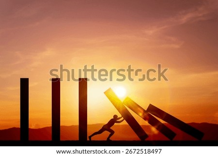 Silhouette of man pushing rectangular blocks down to stop the dominoes with background of light sky sunset. Concept of prevention, and risk management.