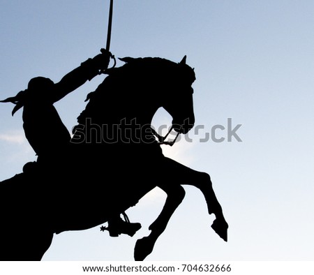 Silhouette of a man riding a horse and holding a sword