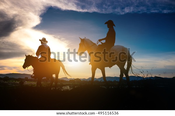 Silhouette of man riding a horse on sunset with\
beautiful background.Three cowboys silhouetted against a dawn sky.\
Montana horse ranch