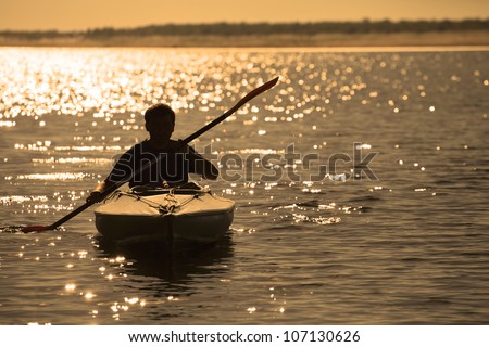Silhouette of a man rowing in the canoe