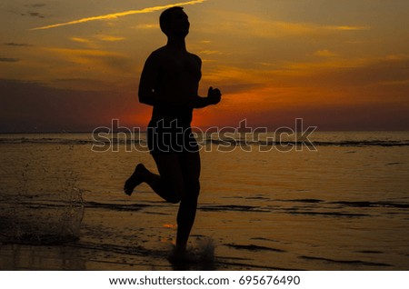 Silhouette of man running on the  beach at sunset.