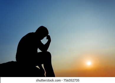 Silhouette of man sitting at sunset - Shutterstock ID 756352735