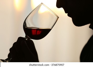 Silhouette of man sniffing red wine in a glass, close up