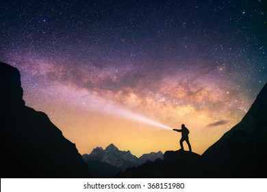 Silhouette of the man standing against the Milky Way in the mountains with a flashlight in his hands. Nepal, Everest region, view of the mount Thamserku (6,608 m) from Thame village (3,750 m).