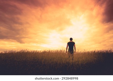 Silhouette Of Man Standing In A Field At Sunset