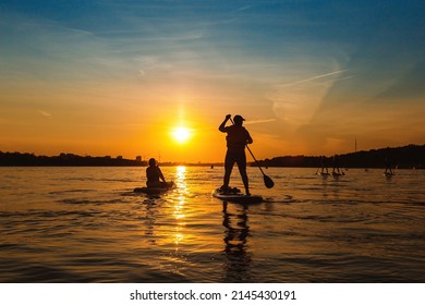 Silhouette man standing up on sapboard. Man ride boat on river at sunset with beautiful view. People has active rest and relax.