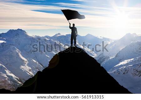 Silhouette Of A Man Standing On Top Of The Mountain Peak Waving Flag