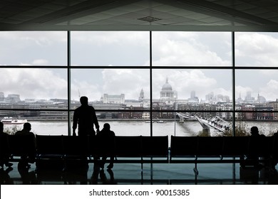 Silhouette Of Man Standing And Seating Waiting At A Lounge With Large Observation Window Showing London City Skyline With St Paul Cathedral, For The Concept Of Immigrants Waiting To Enter Europe.