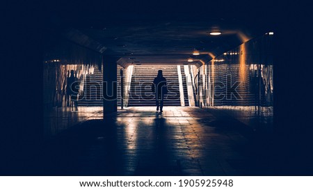 silhouette of man in a subway tunnel. Light at end of tunnel. Person walking down a dark corridor