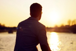 Silhouette Of A Man . Sunset Lake And River Nature Background Beautiful Sky. Businessman Looks Into The Distance And Ponders, Thinks, Dreams.