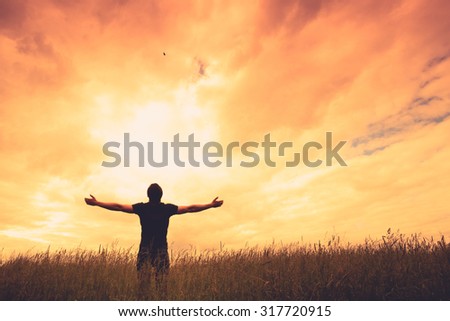 Silhouette of man and sunshine on sky background.
