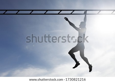 Silhouette of a man swinging across a monkey bar against a surreal blue sky. 