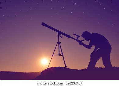 Silhouette Of Man With Telescope On The Rock In River At The Sky Sunset