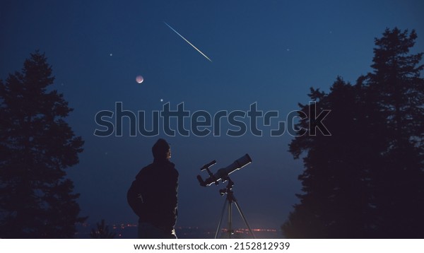 Silhouette of a man, telescope, stars, planets\
and shooting star under the night\
sky.