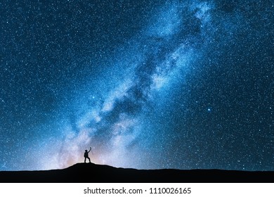 Silhouette of man with trekking poles against amazing Milky Way at night. Space background. Landscape with man on the hill, bright milky way, sky with stars. Beautiful galaxy. Travel. Blue starry sky - Shutterstock ID 1110026165