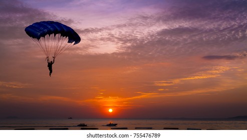 Silhouette man under control  parachute to the beach at sunset time 