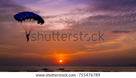 Silhouette man under control  parachute to the beach at sunset time 