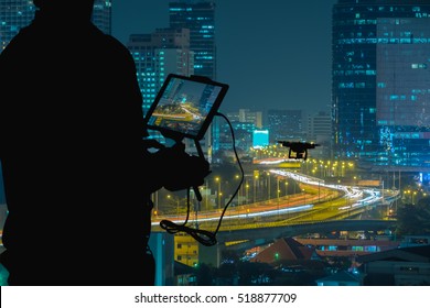 Silhouette Of Man Using Drone To Monitor The City  Night Traffic.