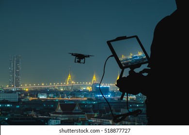 Silhouette Of Man Using Drone To Monitor The City At Night.