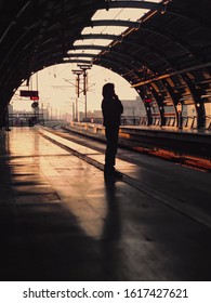 Silhouette of man waiting for the train at platform in train station, sun light in vintage color selective focus, journey and travel concept.