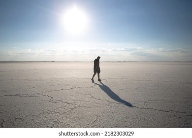 silhouette of man walking alone on dried lake. young man walking alone in the desert