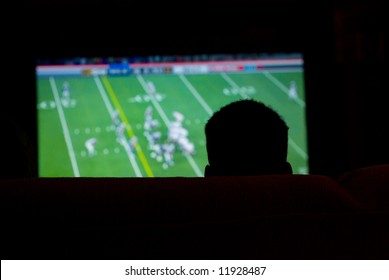 Silhouette Of Man Watching Football Game On Widescreen TV