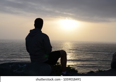 Silhouette Of Man Watching Sun Set Over Sea