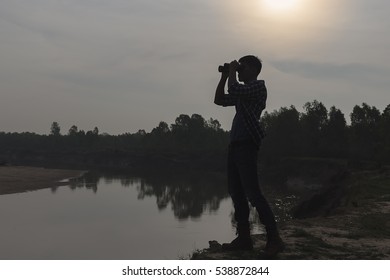 Silhouette of man watching view with binoculars .Hiker with binoculars