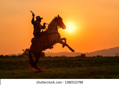 The Silhouette Of A Man Wearing A Cowboy Dress With A Horse And A Gun Held In His Hand