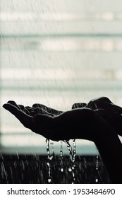 Silhouette Of A Man's Hand Under A Shower Against A Backlit Window.